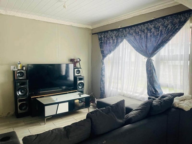 A living room featuring tiled flooring and a tongue and groove ceiling, requiring cosmetic updates to the wall finishes.