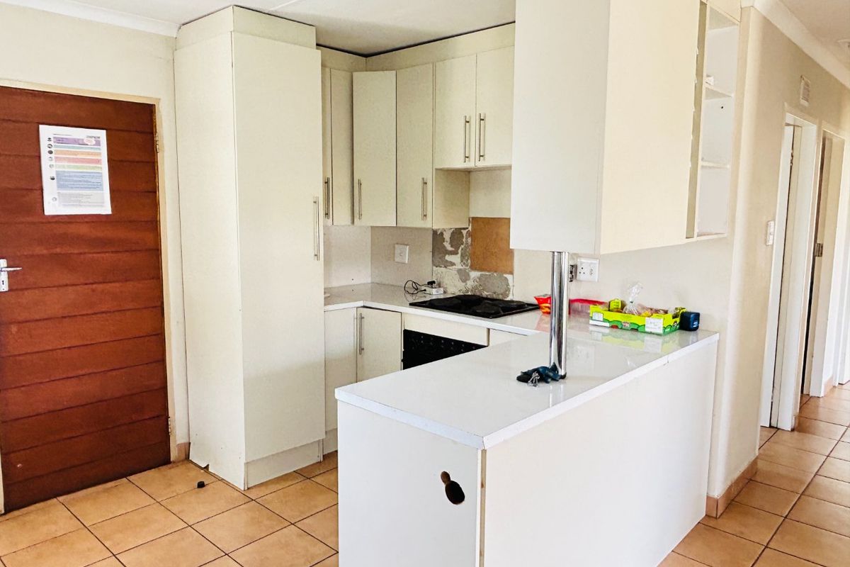 Compact kitchen featuring built-in cabinetry, a breakfast counter, and integrated hob and oven, currently requiring maintenance and cosmetic repairs to the splashback and cabinetry.