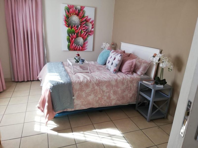 A bedroom featuring tiled flooring and neutral wall tones, providing a functional space with natural light.