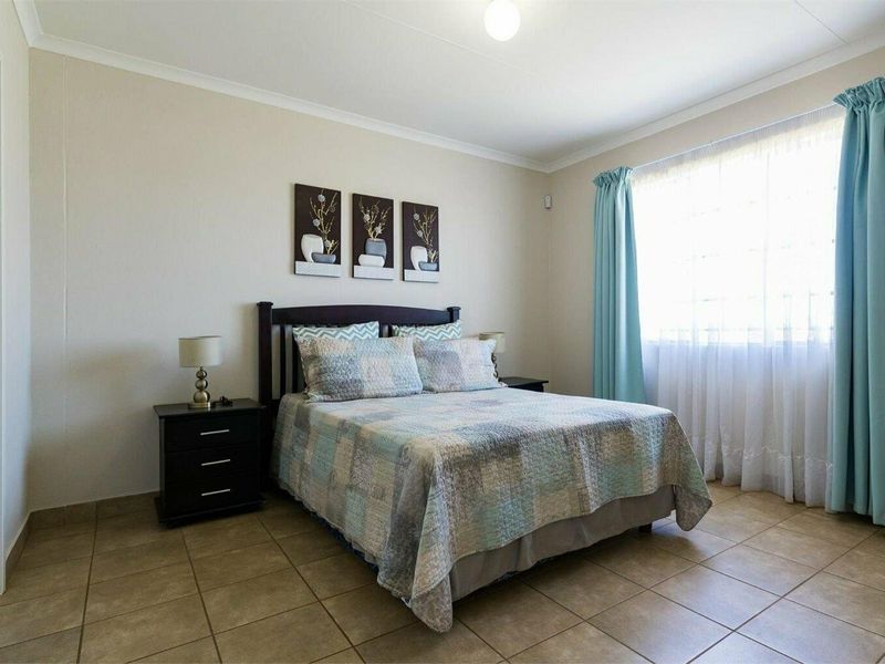 A well-lit bedroom featuring neutral wall tones, tiled flooring, and classic cove cornicing, providing a comfortable and functional living space.