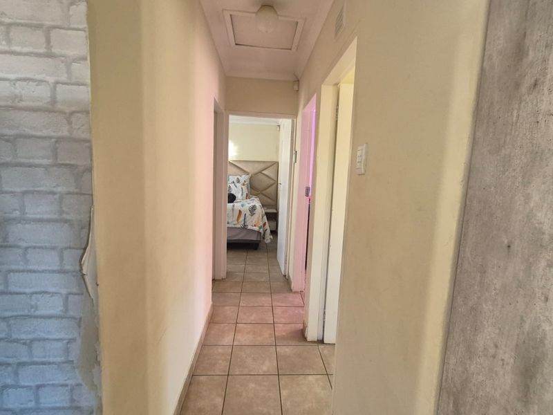 A narrow hallway featuring tiled flooring and a faux brick accent wall, providing access to adjacent rooms.