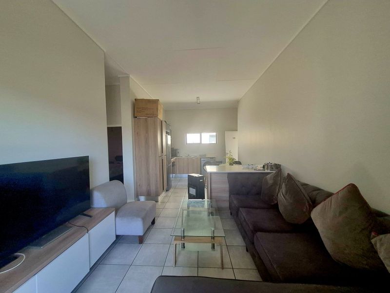 Open-plan living area featuring tiled flooring and a functional kitchen with island, providing a versatile space for dining and relaxation.