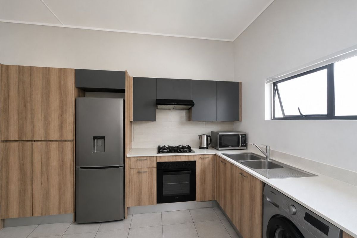 Modern kitchen featuring wood-grain and charcoal cabinetry, stone countertops, integrated gas hob, oven, extractor fan, and double sink with tiled flooring.