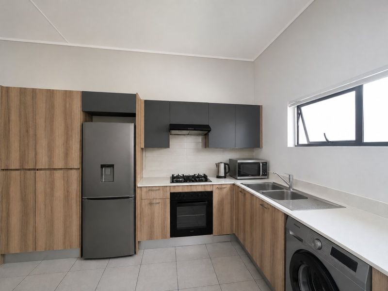 Modern kitchen featuring wood-grain and charcoal cabinetry, stone countertops, integrated gas hob, oven, extractor fan, and double sink with tiled flooring.