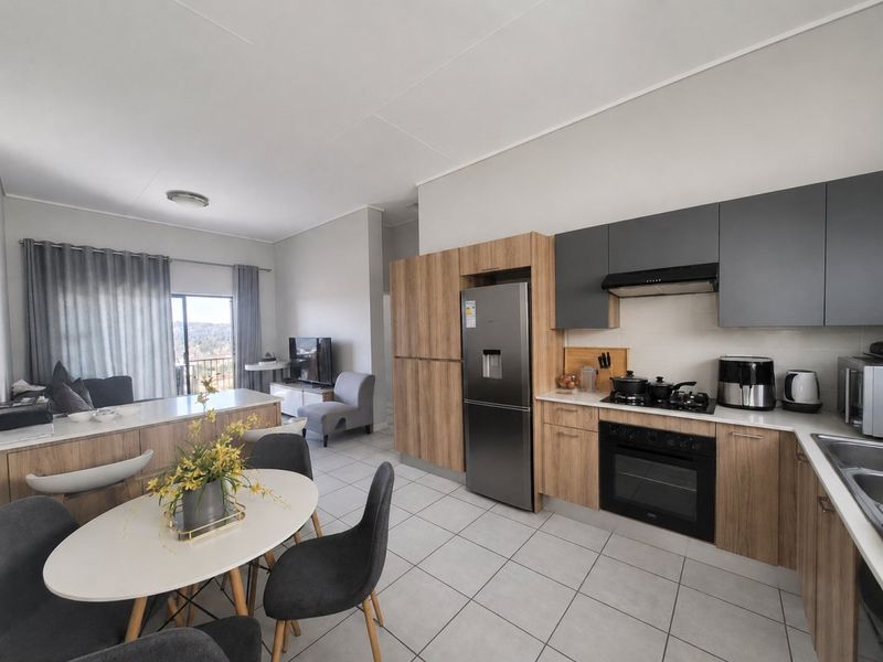 Modern open-plan kitchen and living area featuring contemporary cabinetry, integrated appliances, tiled flooring, and direct access to a balcony.