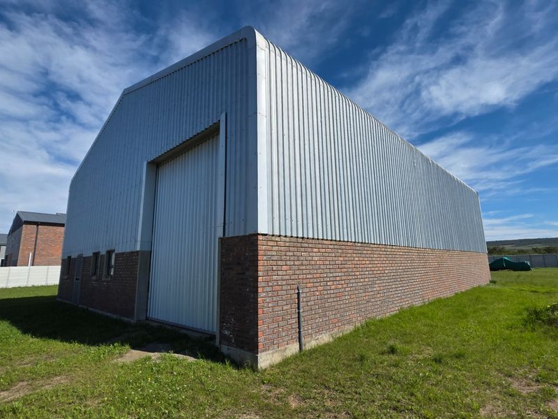 A view of the rear industrial warehouse structure featuring corrugated metal cladding, a face brick base, and a large industrial roller door.