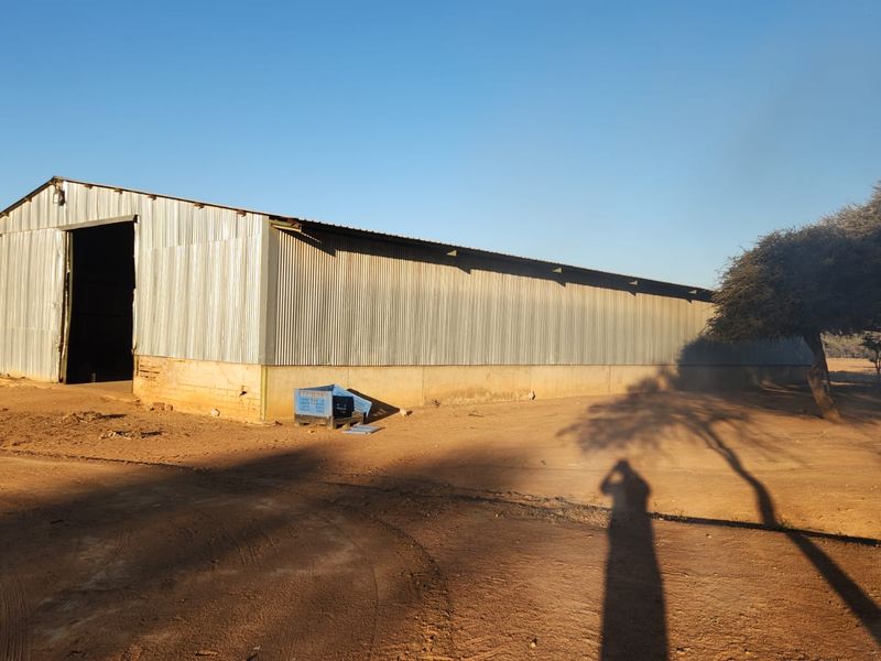 A large agricultural barn featuring corrugated metal siding and a concrete foundation, situated on a rural farm property.