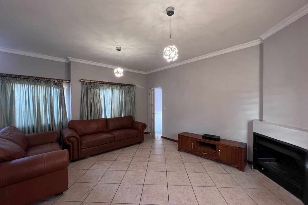 Spacious living room featuring tiled flooring, a built-in fireplace, and decorative pendant lighting, offering a neutral base for interior updates.