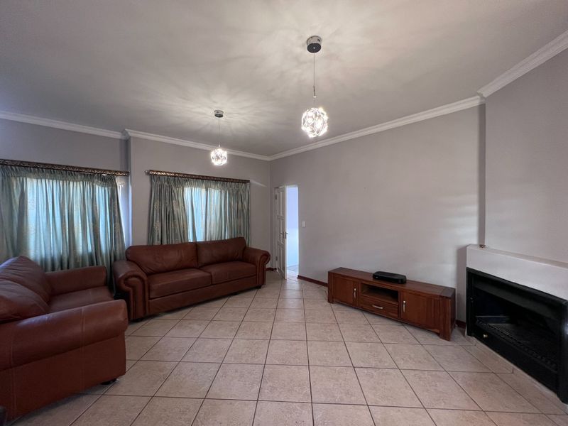 Spacious living room featuring tiled flooring, a built-in fireplace, and decorative pendant lighting, offering a neutral base for interior updates.