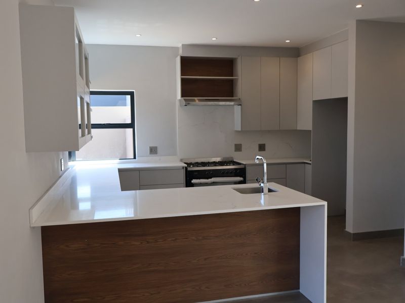 Modern kitchen featuring sleek cabinetry, quartz countertops, a gas hob with extractor, and a breakfast bar, presented in a clean, contemporary finish.