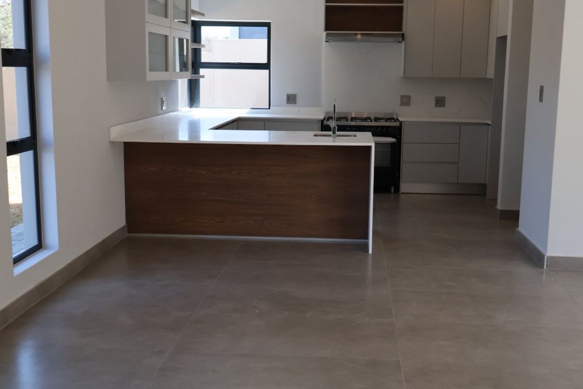 Modern, open-plan kitchen featuring sleek cabinetry, stone countertops, a functional island, and high-quality tiled flooring in a clean, contemporary space.