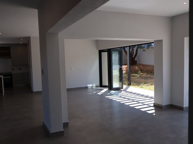 Spacious open-plan living area featuring modern tiled floors, recessed lighting, and bi-fold doors opening to a private garden.
