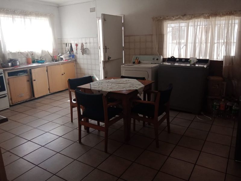 A dated kitchen featuring tiled flooring, built-in cabinetry, and a tiled backsplash, offering potential for a modern renovation and layout update.