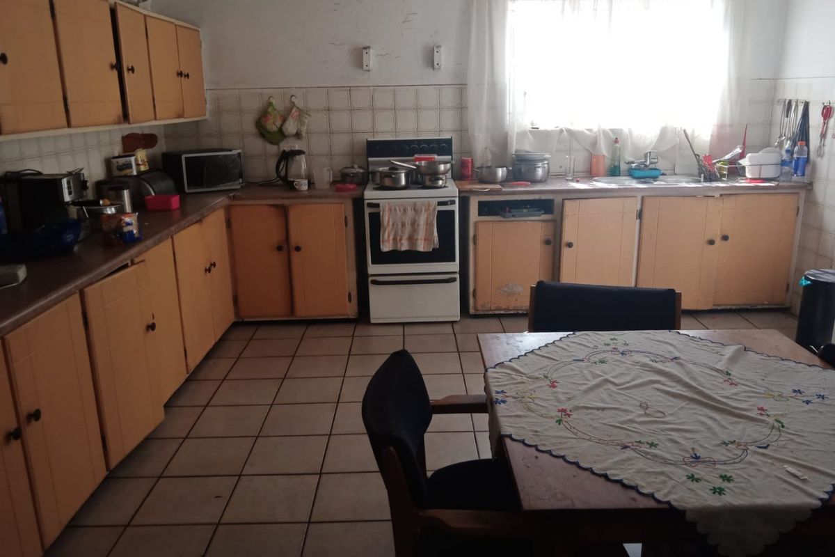 A functional kitchen featuring original cabinetry, tiled flooring, and a freestanding stove, offering significant potential for modernization and cosmetic updates.