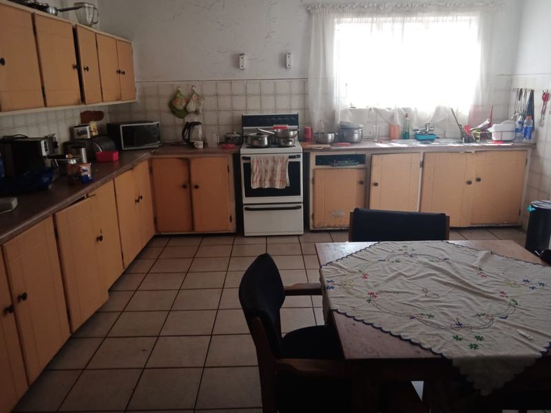 A functional kitchen featuring original cabinetry, tiled flooring, and a freestanding stove, offering significant potential for modernization and cosmetic updates.