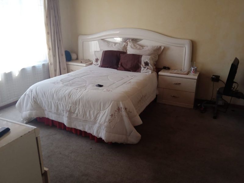 A bedroom featuring carpeted flooring and a built-in headboard. The room shows signs of wear and would benefit from cosmetic updates.