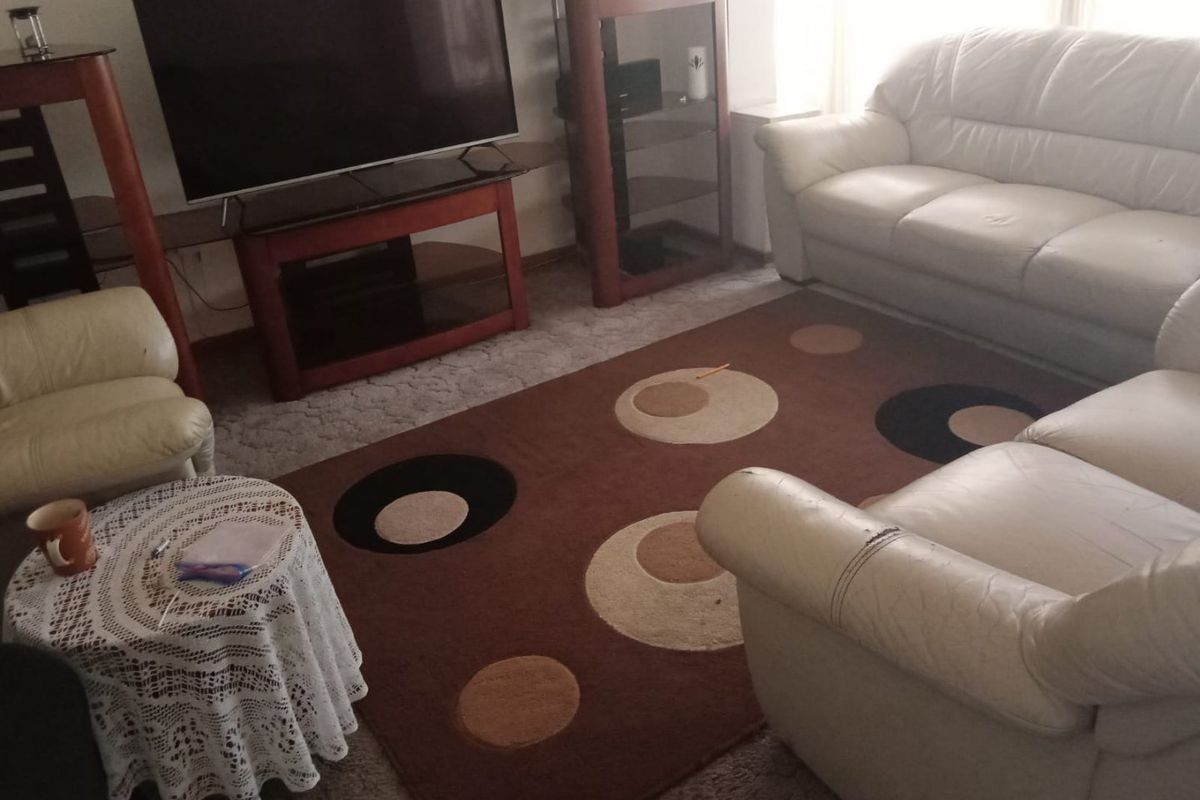 A comfortable living room area featuring carpeted flooring and neutral wall finishes, providing a functional space for relaxation and entertainment.