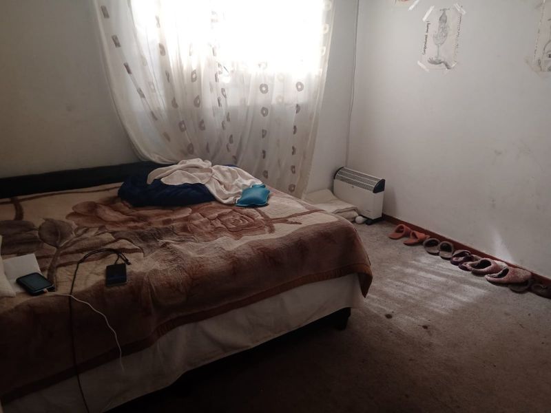 A bedroom featuring carpeted flooring and a window with curtains, requiring cosmetic updates to improve the overall condition of the space.