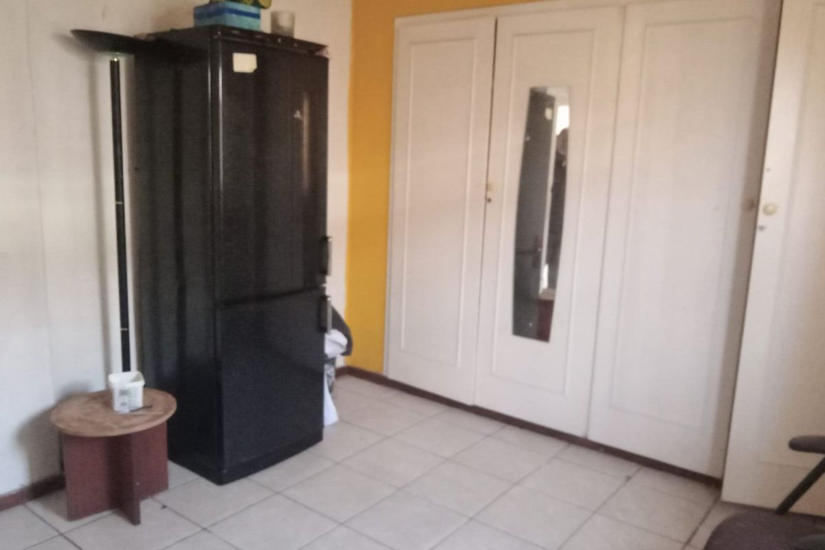 A bedroom featuring built-in cupboards and tiled flooring, requiring cosmetic updates to improve the overall aesthetic and condition.