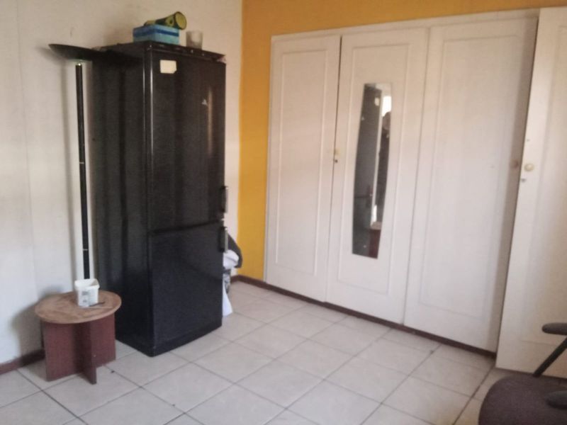 A bedroom featuring built-in cupboards and tiled flooring, requiring cosmetic updates to improve the overall aesthetic and condition.