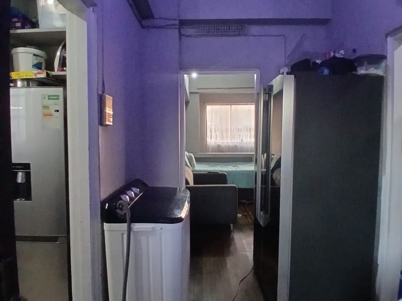 A narrow hallway area featuring timber flooring and visible ventilation, connecting to adjacent living and utility spaces.