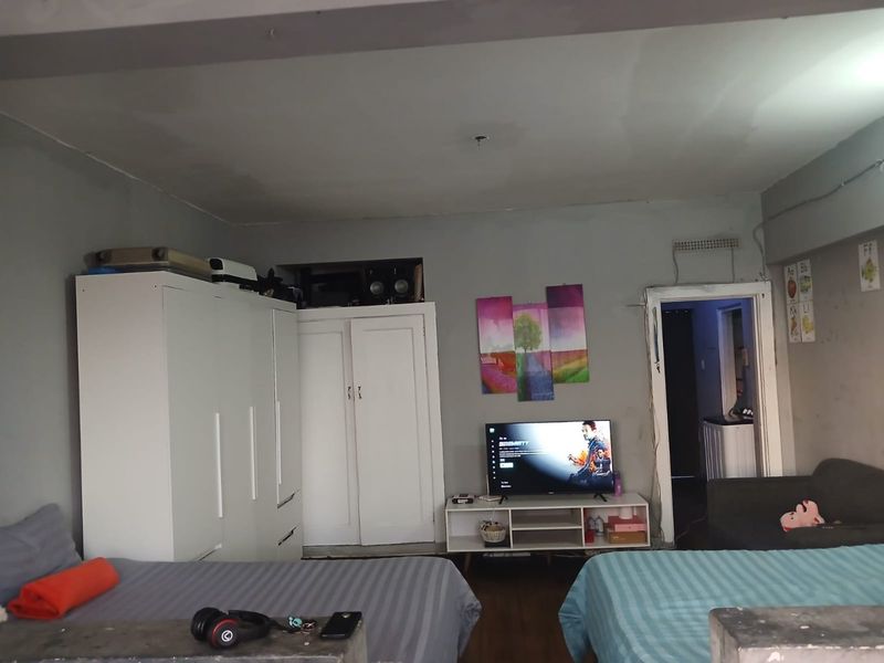 A bedroom featuring built-in cupboards and access to an adjoining space, requiring cosmetic updates to the walls and ceiling to improve the overall finish.