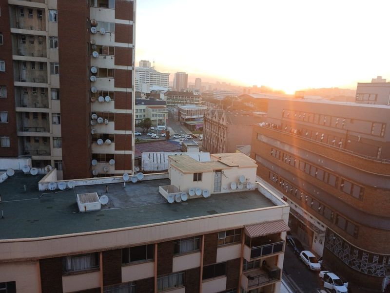 An elevated urban view overlooking surrounding apartment buildings and city streets during sunset.