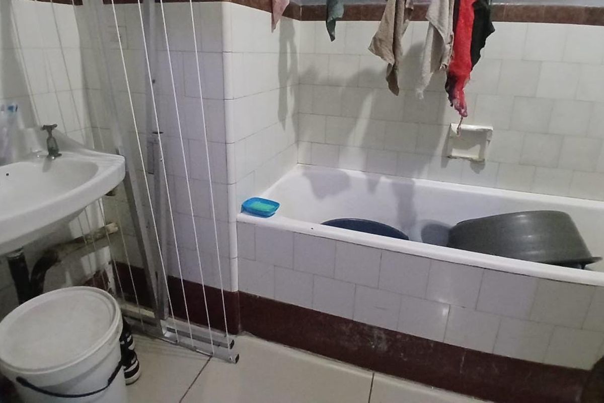 A dated bathroom featuring a pedestal basin and a tiled bathtub, requiring cosmetic updates and maintenance to improve its overall condition and appeal.