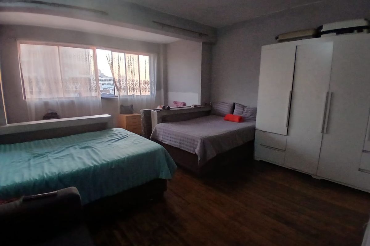 Spacious bedroom featuring laminate flooring, a large window for natural light, and a built-in wardrobe for storage.