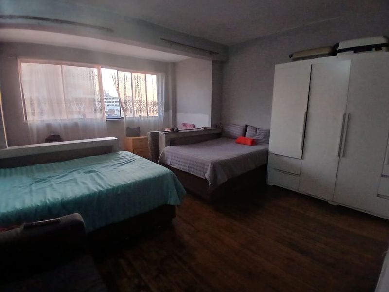 Spacious bedroom featuring laminate flooring, a large window for natural light, and a built-in wardrobe for storage.