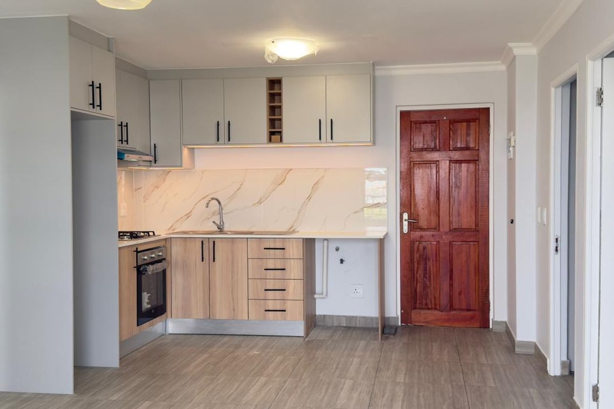 Modern kitchen featuring light wood and grey cabinetry, marble-look splashback, built-in oven, gas hob, and tiled flooring in an open-plan layout.
