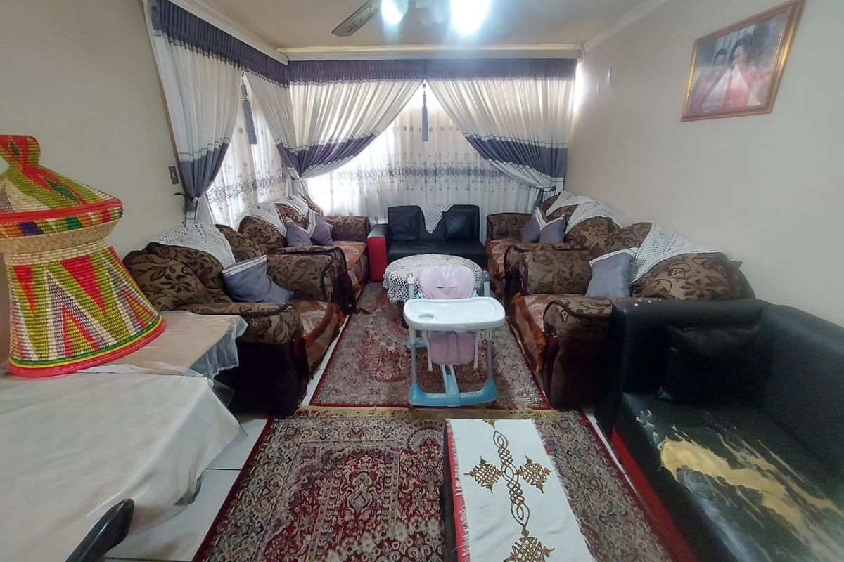 A spacious living room featuring tiled flooring and a ceiling fan, offering a comfortable area for relaxation and family gatherings.