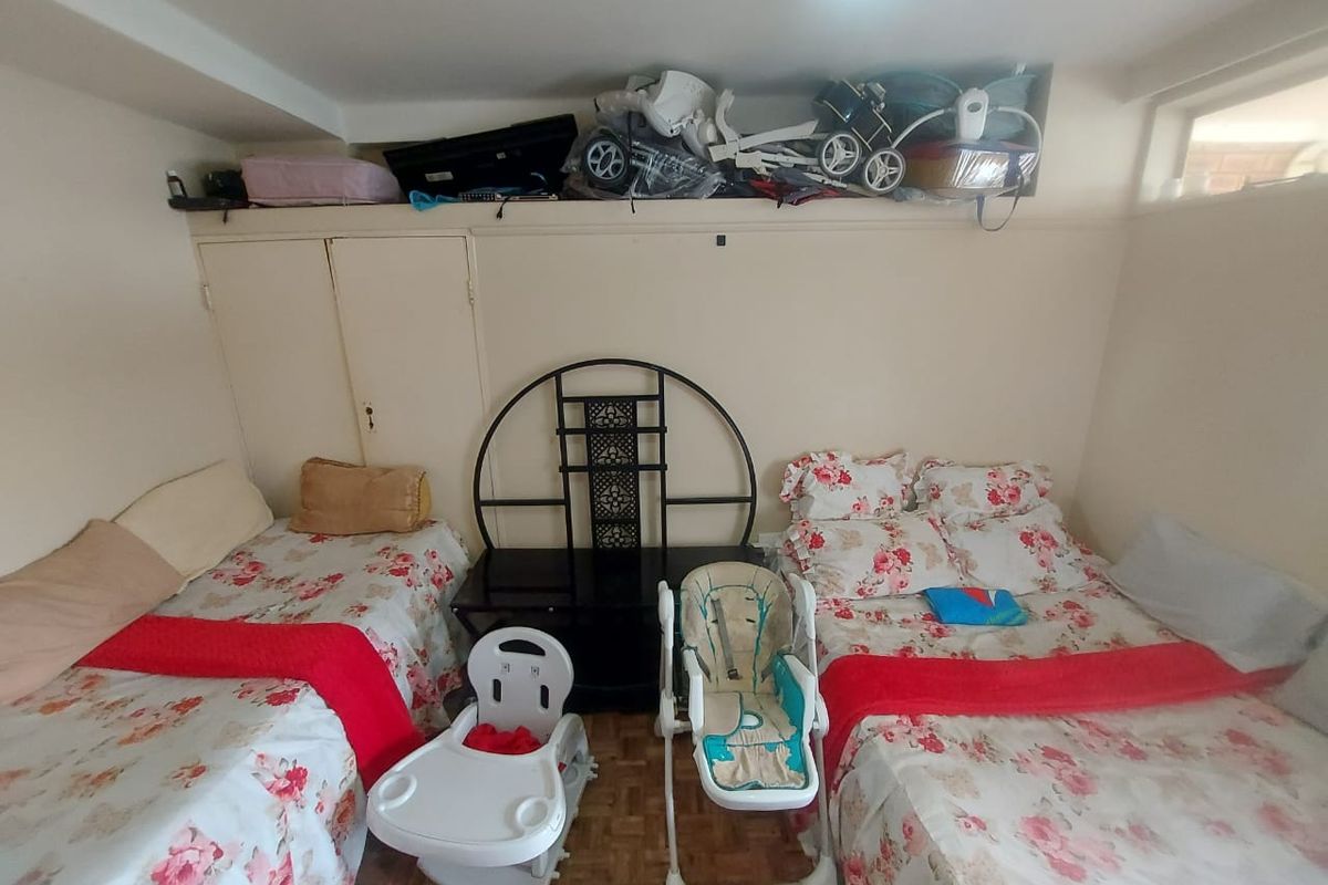 A bedroom featuring parquet flooring and a built-in cupboard, providing functional storage space within the room.