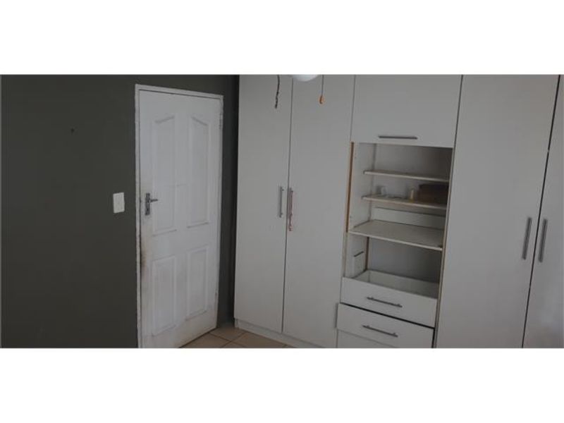 Bedroom featuring built-in white cupboards with an open shelving section and a standard internal door.