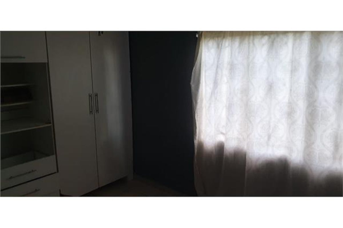 A bedroom featuring a built-in wardrobe and a window with curtains.
