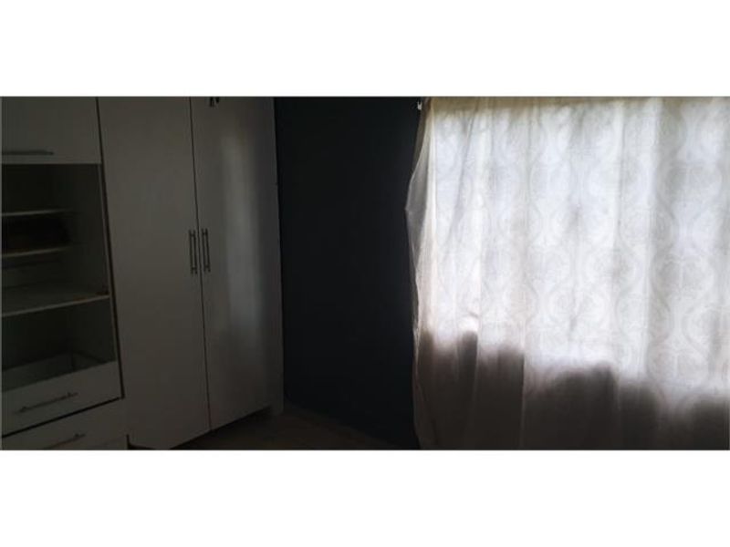 A bedroom featuring a built-in wardrobe and a window with curtains.