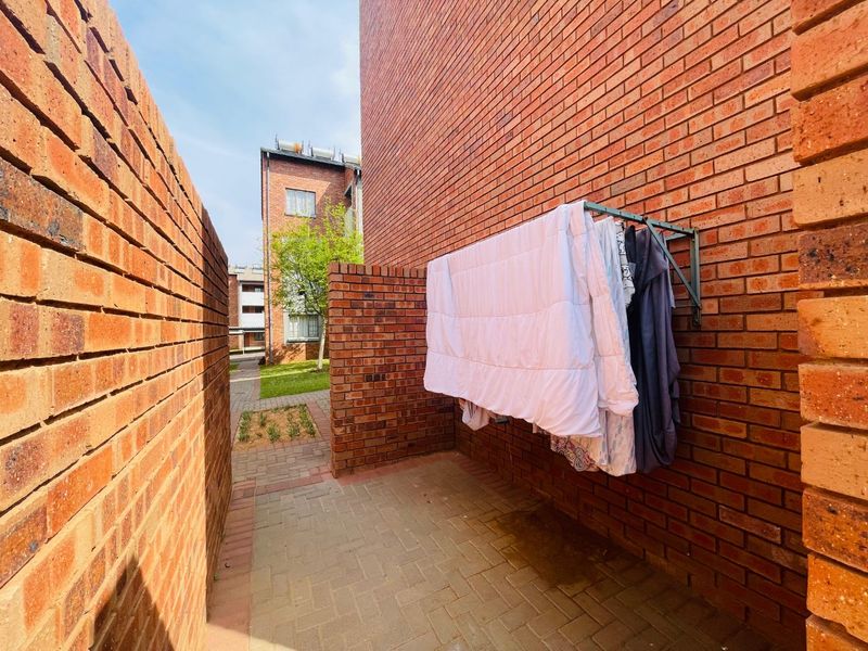 A private rear courtyard area featuring exposed brick walls and paved flooring, providing a functional outdoor space for the apartment.