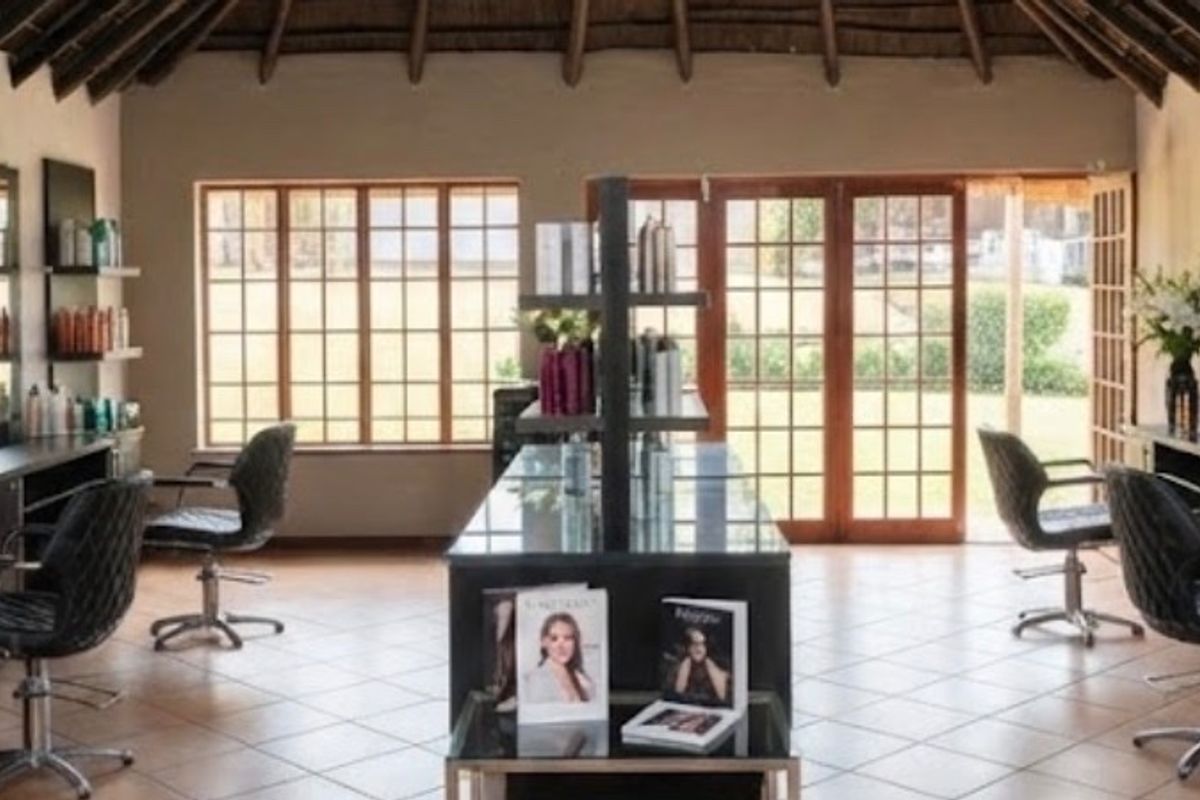 A well-maintained commercial salon space featuring built-in vanity stations, large mirrors, tiled flooring, and an exposed thatch roof with natural light access.