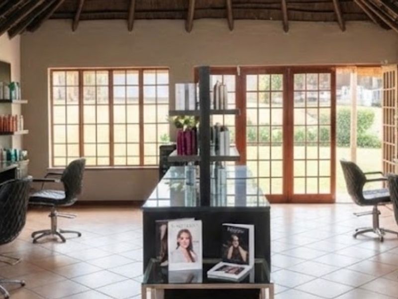 A well-maintained commercial salon space featuring built-in vanity stations, large mirrors, tiled flooring, and an exposed thatch roof with natural light access.