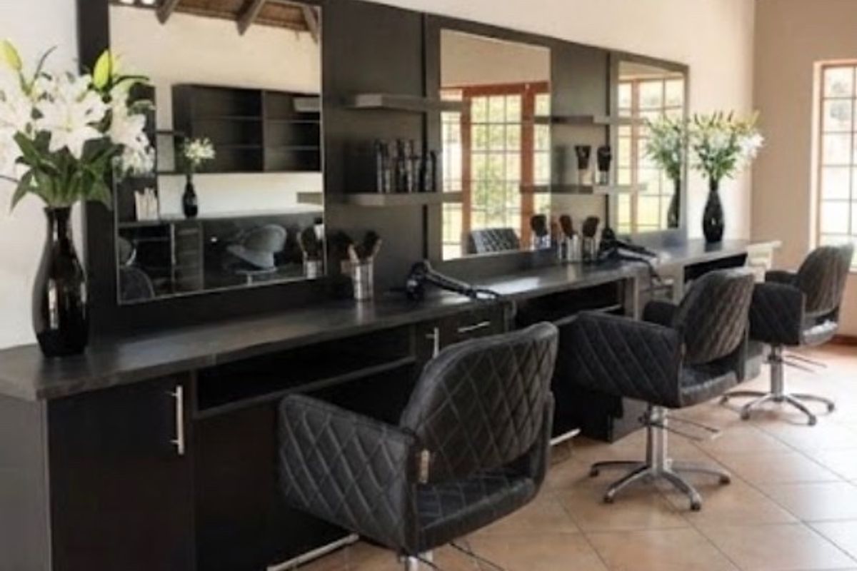 A professional salon space featuring built-in vanity stations with integrated mirrors, tiled flooring, and exposed timber rafters.
