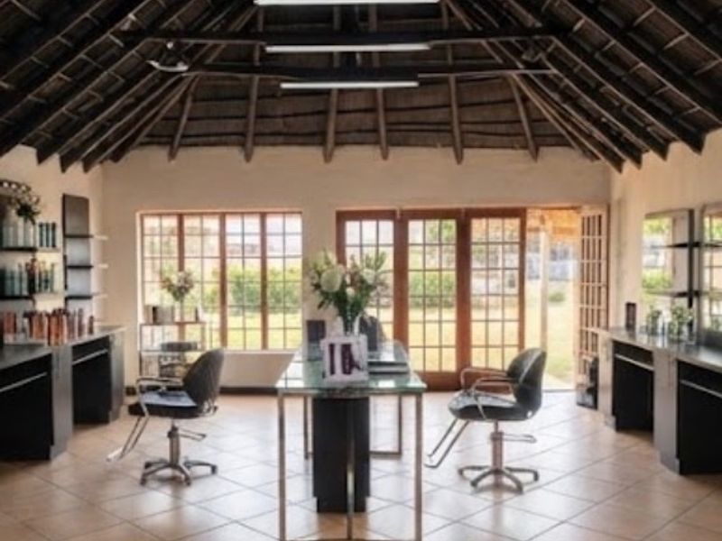 Spacious commercial salon area featuring high exposed timber thatched ceilings, ceramic tiled flooring, and abundant natural light through large windows and french doors.