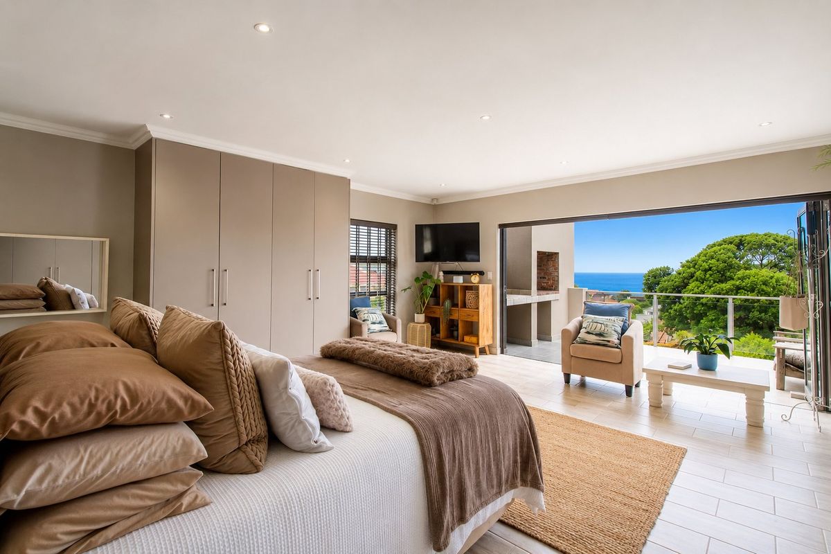 Spacious bedroom featuring built-in cupboards, tiled flooring, and large sliding doors opening onto a balcony with scenic ocean views.