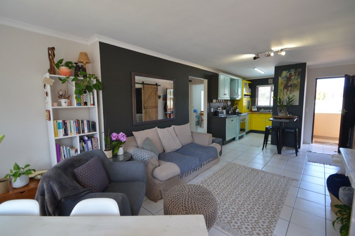 Open-plan living area featuring a combined kitchen with vibrant cabinetry, tiled flooring, and direct access to an outdoor balcony space.