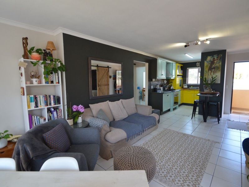 Open-plan living area featuring a combined kitchen with vibrant cabinetry, tiled flooring, and direct access to an outdoor balcony space.