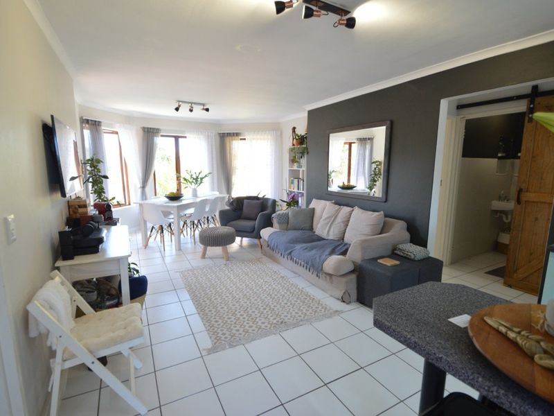 Spacious open-plan living and dining area featuring tiled flooring, large windows for natural light, and a modern sliding barn door leading to an adjacent room.