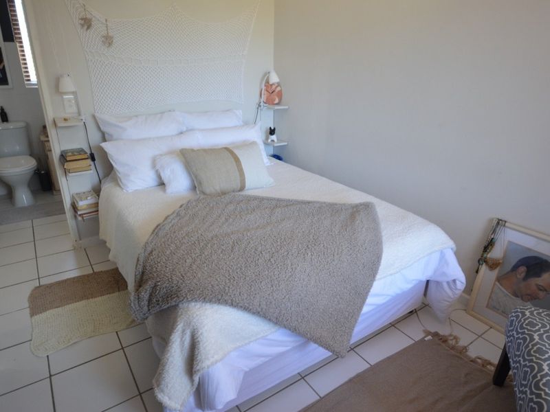 A compact bedroom featuring tiled flooring and an integrated en-suite toilet, offering a functional layout for a small apartment space.