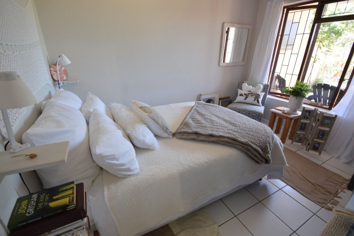 A cozy bedroom featuring tiled flooring and a window with a security gate, offering a bright and functional living space.