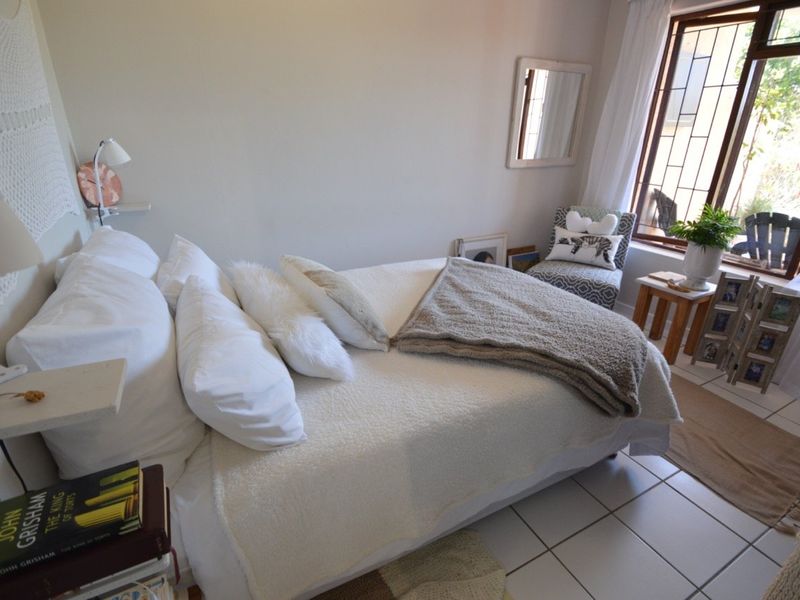 A cozy bedroom featuring tiled flooring and a window with a security gate, offering a bright and functional living space.