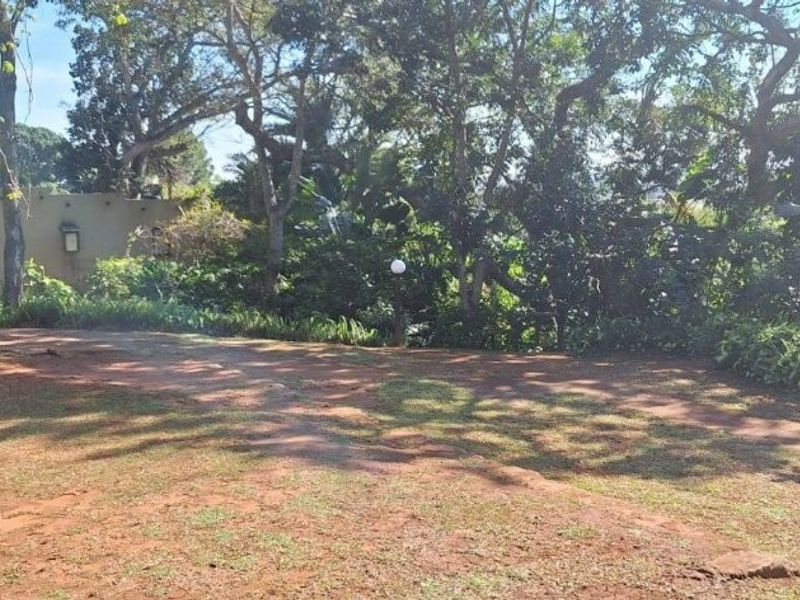 A spacious garden area featuring mature trees and established landscaping, providing a natural outdoor setting for the property.