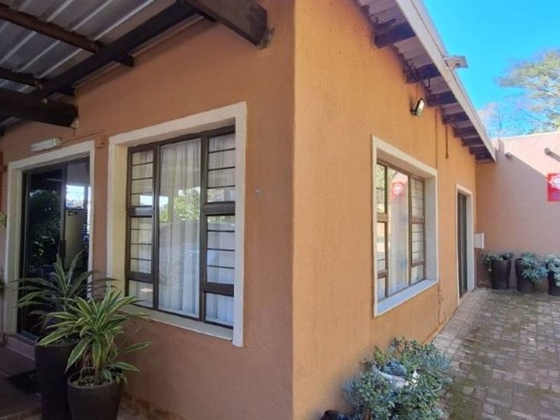 A view of the rear exterior of the townhouse, featuring a covered patio area with tiled flooring and a paved walkway along the side.